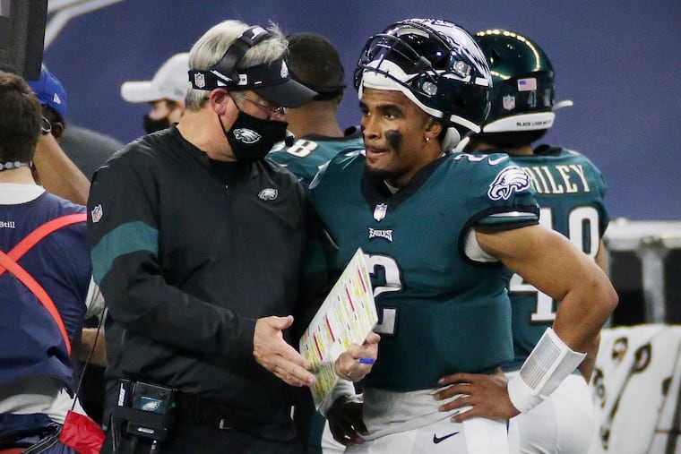 Eagles coach Doug Pederson talks with quarterback Jalen Hurts (2) during the game Sunday against the Dallas Cowboys at AT&T Stadium in Arlington, Texas.