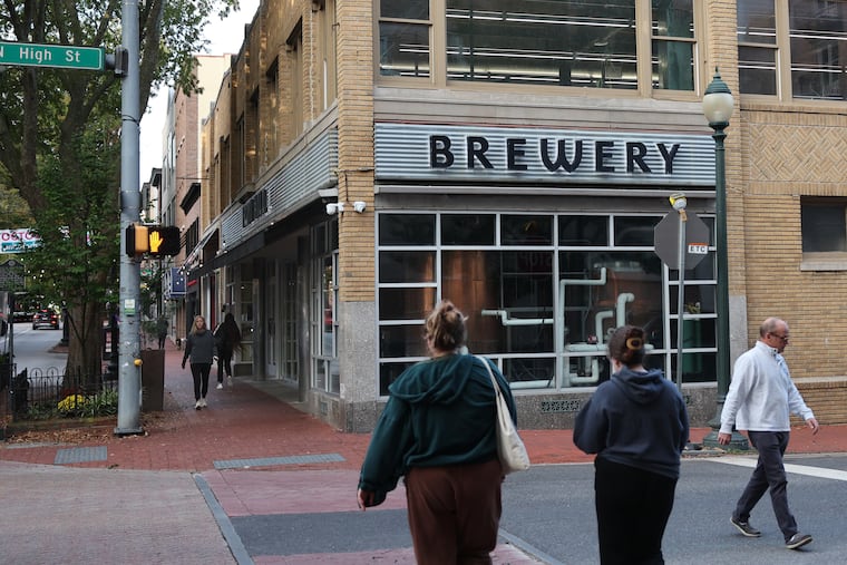 People walk by the closed Iron Hill Brewery in West Chester in October.