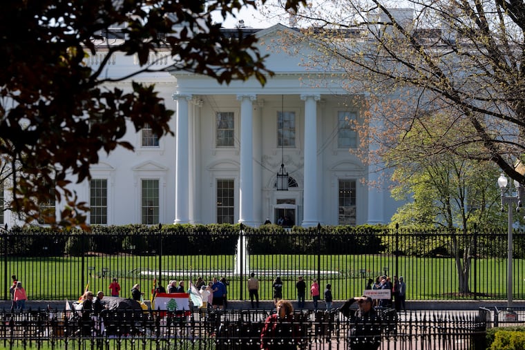 People look through the fence at the White House, Tuesday, April 1, 2025, in Washington. A new proposal would fence off the ends of the area to prevent pedestrian access if there is a security risk.