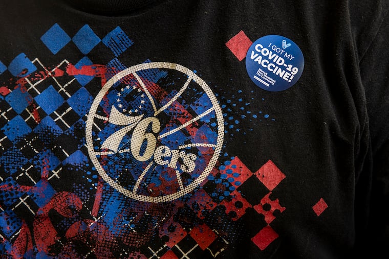 A man wearing a 76ers shirt received a sticker after getting his COVID-19 vaccination at the Preparatory Charter School in South Philadelphia on April 10.