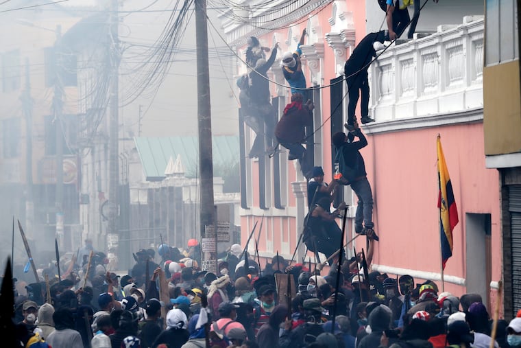 Anti-government demonstrators scale the facade of a residence to reach the rooftop, looking for a better vantage point to battle with police, in Quito, Ecuador, in October 2011.