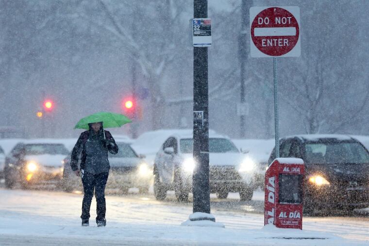 A pedestrian braves the snow with an umbrella near 23rd and Spring Garden streets as snow falls on Friday, Dec. 15, 2017. TIM TAI / Staff Photographer