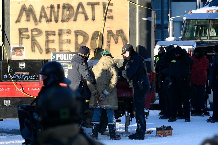 Royal Canadian Mounted Police officers take a protester into custody as police take action to put an end to a protest in Ottawa.