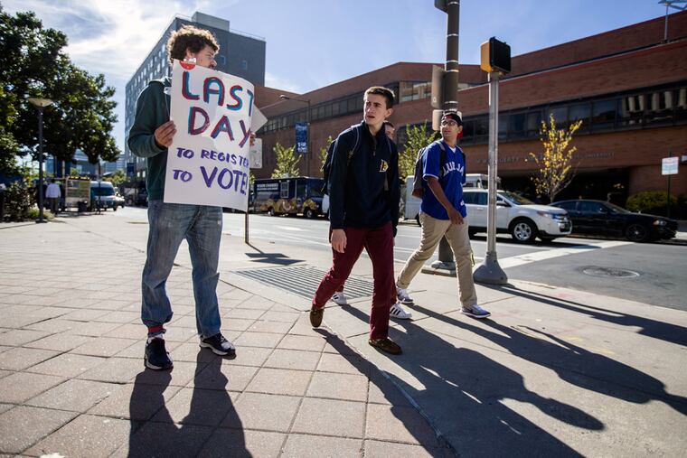 Allister Blossfeld, an organizer for Nextgen Climate, stands with a "Last Day to Register to Vote" sign on the corner of Market and 33rd Streets on the Drexel campus.