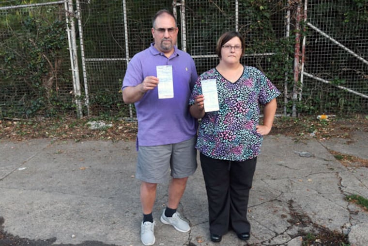 John Melone holding his son’s girlfriend’s ticket with neighbor Samantha Zeno holding her ticket for parking in front of the gate. (STEVEN M. FALK / STAFF PHOTOGRAPHER)