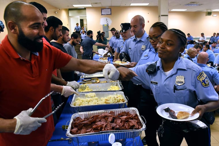 Officer Alvina McClain fist-bumps volunteer Mohammed Darsalim as she and fellow officers work their way through the breakfast line before reporting for duty at the Puerto Rican Day Parade.
