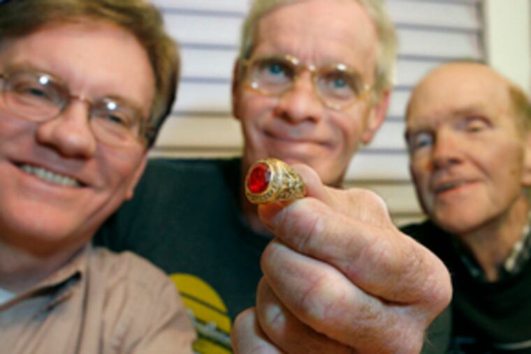 Kin of the late Mary Dignam McLaughlin examine a treasure of hers: the class ring of Robert J. Reilly, her fiance who was killed in World War II before they could be married. They are (from left) her sons Kevin and Ed McLaughlin, and her younger brother Jim Dignam.