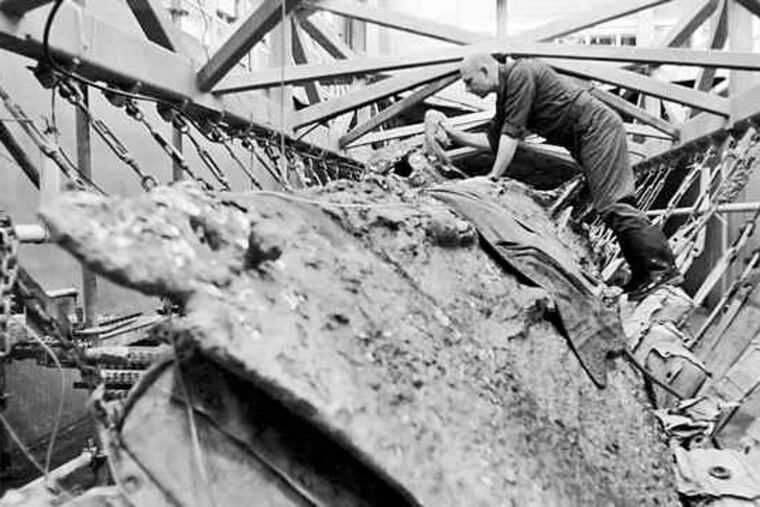 Paul Mardikian, the head conservator on the Hunley project, puts wet towels on the Confederate submarine. In the next phase of conservation, scientists will remove the hardened sediment on the outside of the vessel, perhaps yielding some fresh clues.