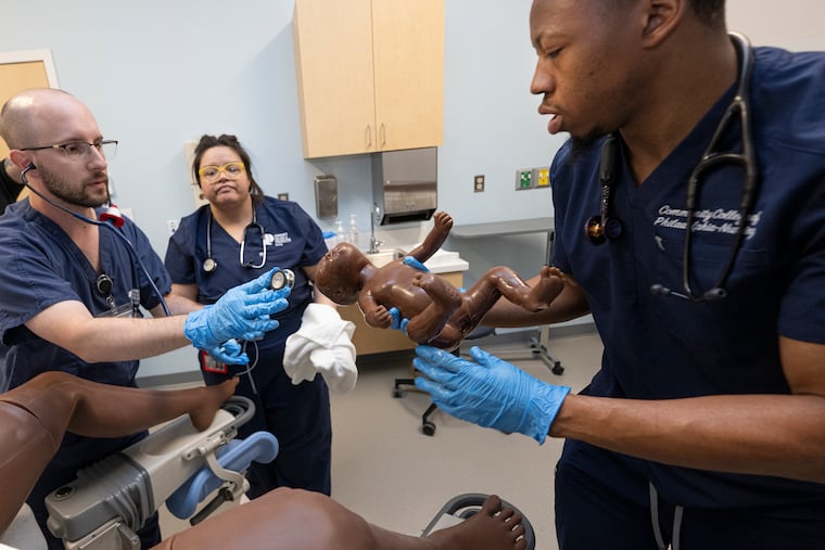 Ridge M. Bair, left, Edna Perrusquia, center, and Aahmid Mink, nursing students at Community College of Philadelphia, take part in a newborn delivery exercise in the school's new simulation lab. The lab uses realistic mannequins to replicate medical scenarios ranging from emergencies to childbirth.