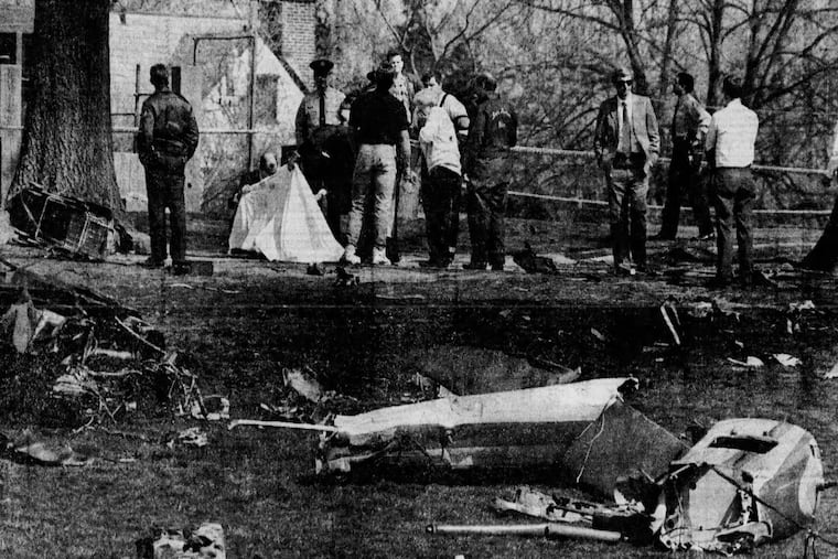 Behind pieces of the wreckage in the schoolyard in 1991, a woman puts her hands to her mouth as she identifies a child under the sheet.