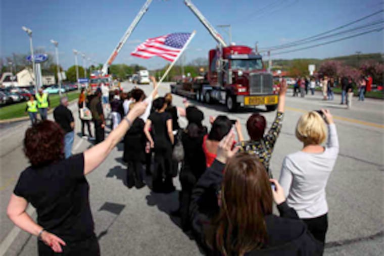 Steel beams from the World Trade Center pass on Route 30 in Exton beneath ladders from the Goshen and Newtown Fire Companies. (Laurence Kesterson / Staff Photographer)