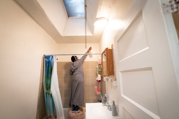 Georgia Knox, shown here wearing a mask and working to spray and disinfect black mold in the bathroom of her home in 2022.