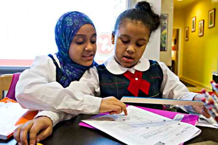 Suaad Dorsey (left), 10, helps her sister Juwaireyah, 8, with her measurement homework at Mighty Writers, Christian St., Philadelphia, February 19, 2013. ( DAVID M WARREN / Staff Photographer )