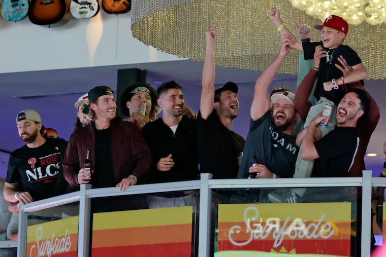 Phillies players look on as Kyle Schwarber and Garrett Stubbs lift up Liam Castellanos during a celebration at Xfinity Live! on Thursday.