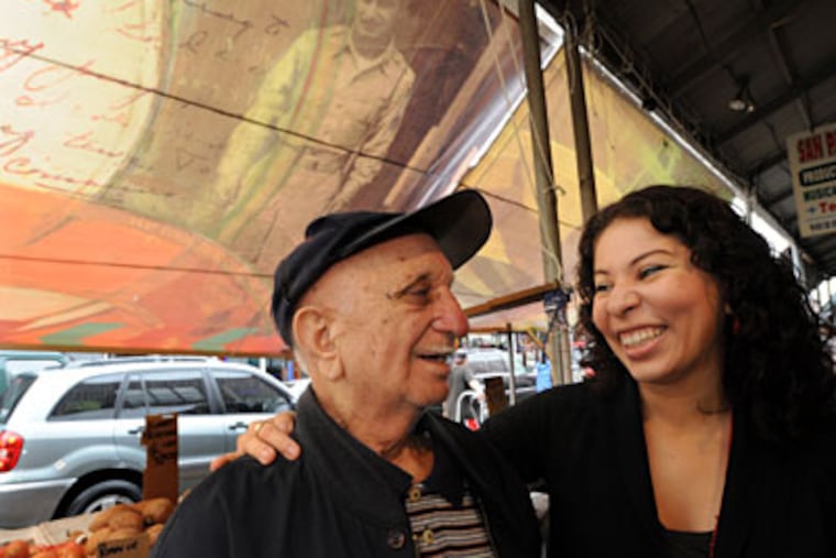 Artist Michelle Ortiz and Tony Messina stand under an Italian Market awning on which Ortiz has drawn Messina's likeness. (APRIL SAUL / Staff)