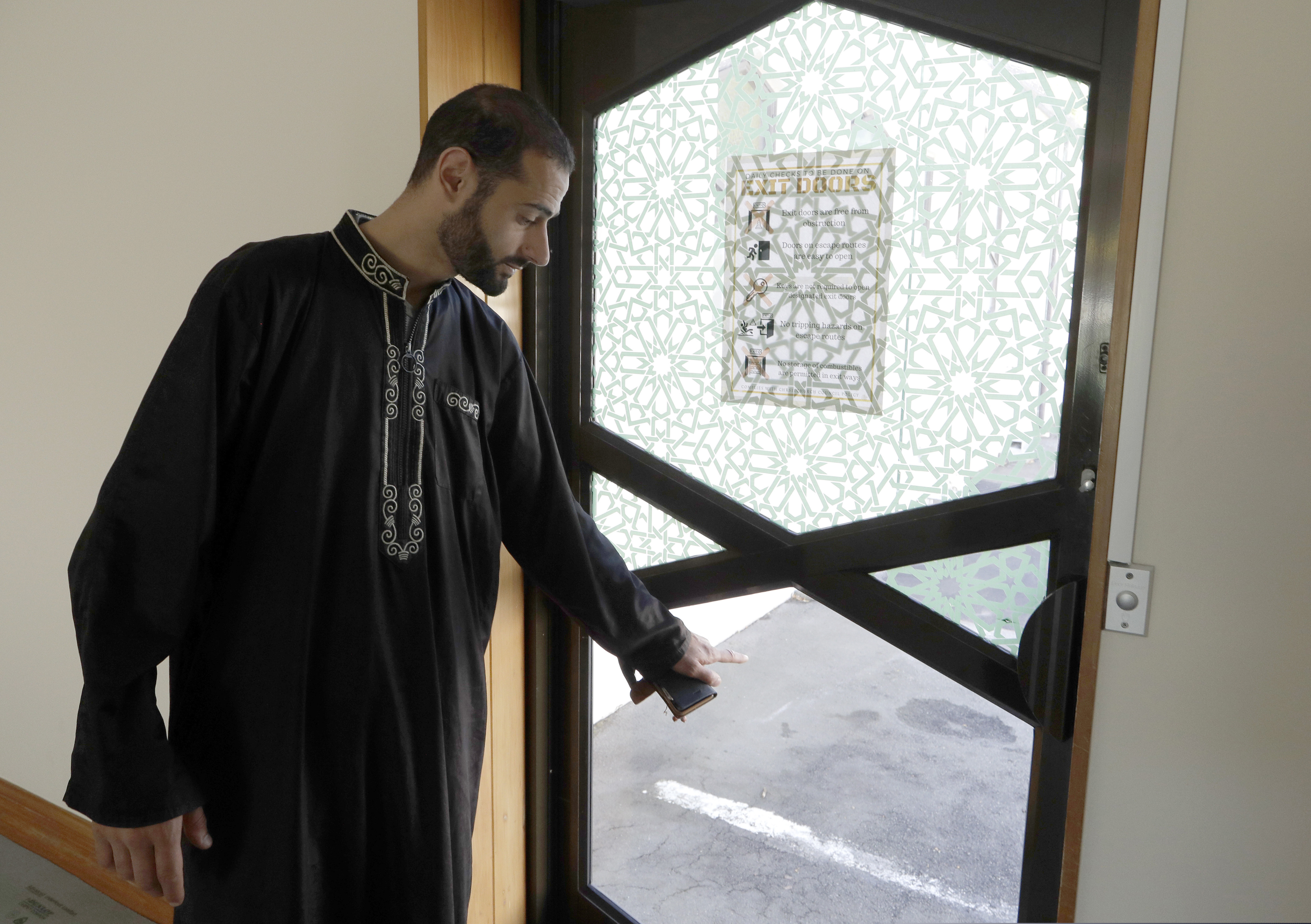 In this March 27, 2019, photo, Al Noor mosque volunteer Khaled Alnobani gestures as he explains his escape through a glass door panel when a gunman burst into the mosque on March 15 in Christchurch, New Zealand. Alnobani says he thinks as many as 17 people may have died trying to get out through the door.