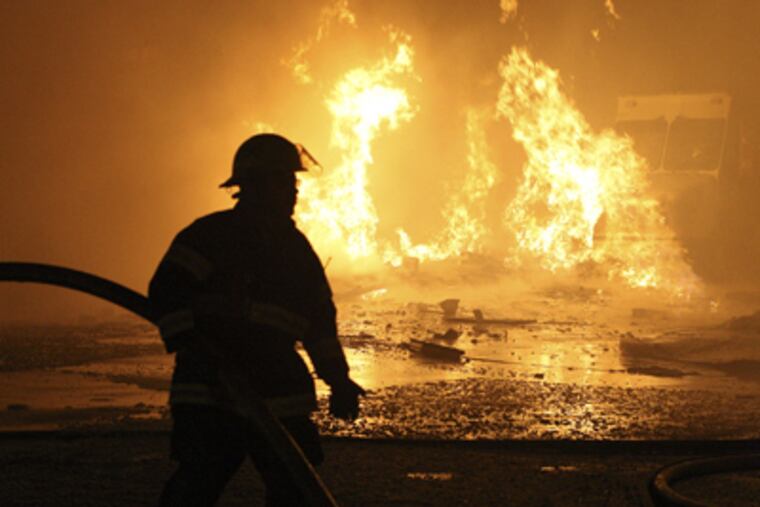 A gas explosion occurs at 6900 Torresdale Avenue in Northeast Philly on Tuesday. A firefighter moves a hose line at the scene. (Steven M. Falk / Staff Photographer)