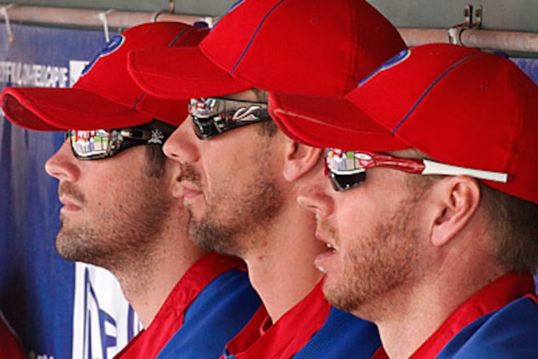 Philadelphia Phillies pitchers Cole Hamels, left, Cliff Lee, center, and Roy Halladay sit in the dugout. (AP Photo/Gene J. Puskar)