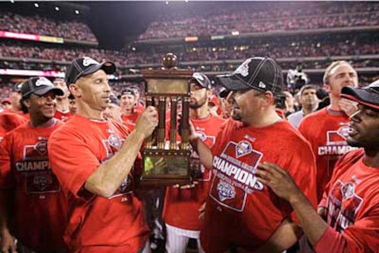 Raul Ibanez, left and Scott Eyre, right, grip the National League trophy after beating the Dodgers last night in Game 5 of the NLCS. (Michael Bryant / Staff Photographer)