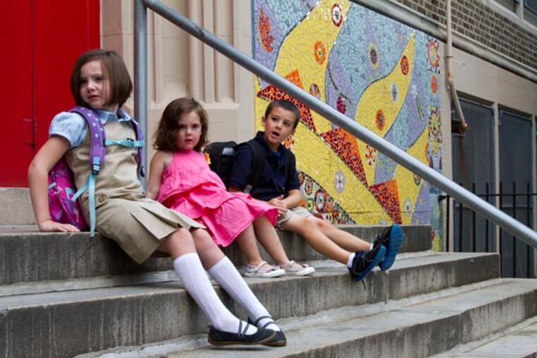 First-graders (left) Claire Dwyer, 6, and (right) Giovanni Piscitelli, 6, sit on the steps of Andrew Jackson Elementary School in Philadelphia. In the center is Claire's sister, Celeste Dwyer, 3, September 3, 2013. (DAVID M WARREN / Staff Photographer)