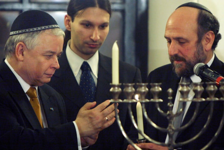 President Lech Kaczynski (left) passes candle to Rabbi Schudrich.