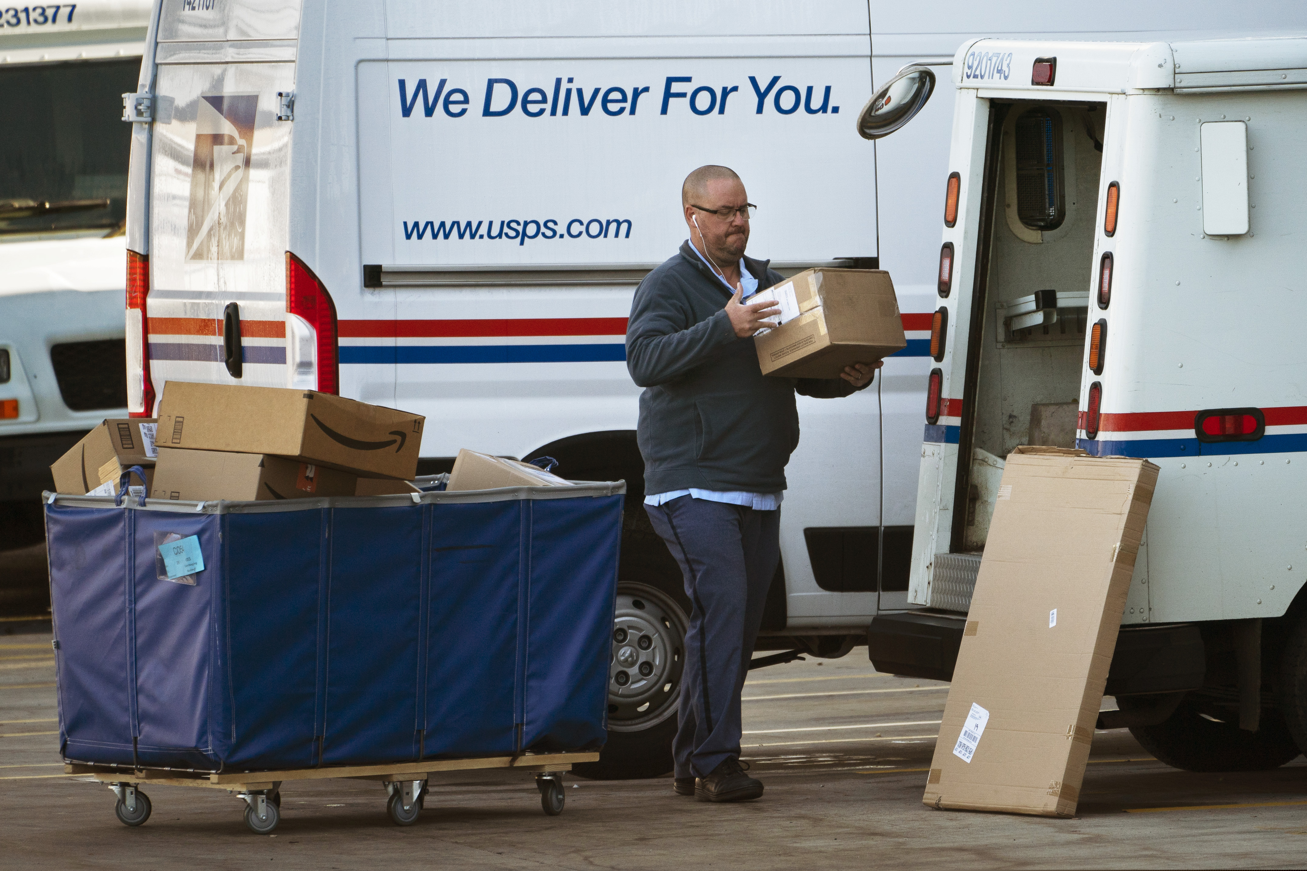 A postal carrier loads boxes into his delivery vehicle in Portland, Maine, in November 2021. Cardboard box production is down, which may be an indication people are expected to buy less.