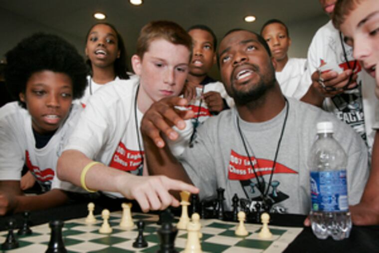 Under a heavy blitz from kibitzers, Thomas Tapeh looks up for a way out on the board. The Eagles' stadium was opened for a tourney to show players from tough areas "that we're cheering for you."