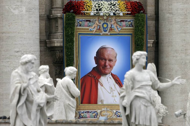 The tapestry showing Pope John Paul II hangs from the facade of St. Peter's Basilica during a solemn celebration led by Pope Francis I where two Popes, John Paul II and John XXIII, were canonized, in St. Peter's Square at the Vatican, Sunday, April 27, 2014. (AP Photo/Alessandra Tarantino)