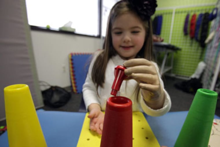 Annabelle Murphy, 5, who was born without a left hand and forearm, practices with her myoelectric hand and arm at the Children's Hospital of Michigan in Detroit. (Eric Seals / Detroit Free Press)
