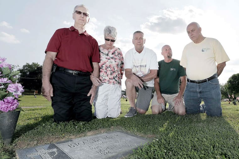 Paul Brasberger's siblings (from left) Jim Brasberger, Susan Murray, Joe Brasberger, Mark Brasberger, and Tony Brasberger surround his grave at St. Mary's Cemetery in Bellmawr. As they seek answers, the prosecutor noted: "The case is never closed."