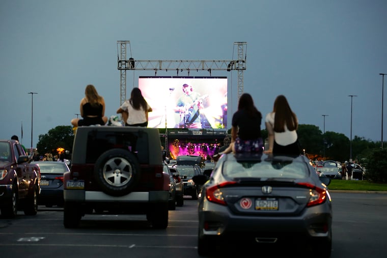 Fans sit on their cars watching The Front Bottoms perform during the Live-In Drive-In series at the Citizens Bank Park parking lot in South Philadelphia on Sunday, August 23, 2020. The drive-in concert series feature live performances on stage in the parking lot at Citizens Bank Park.