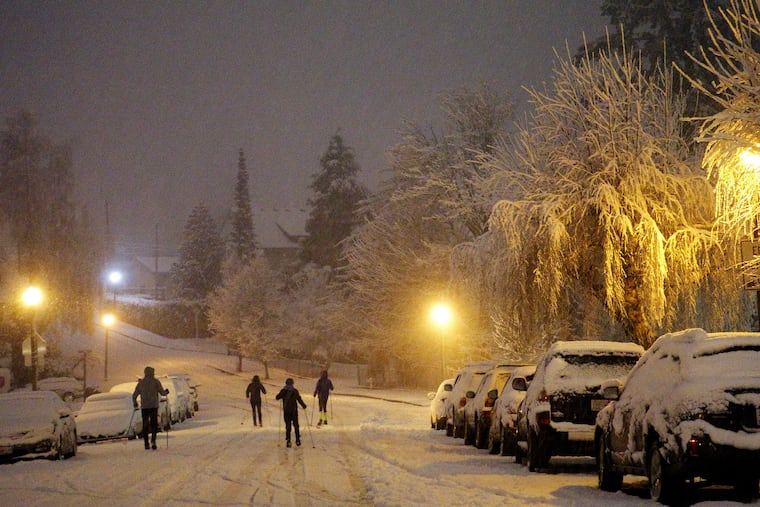 Cross country skiers travel on a street in Tacoma, Wash., the night of Friday, Feb. 8, 2019, during a storm that dropped inches of snow throughout the region and left trees and cars coated in snow and ice.