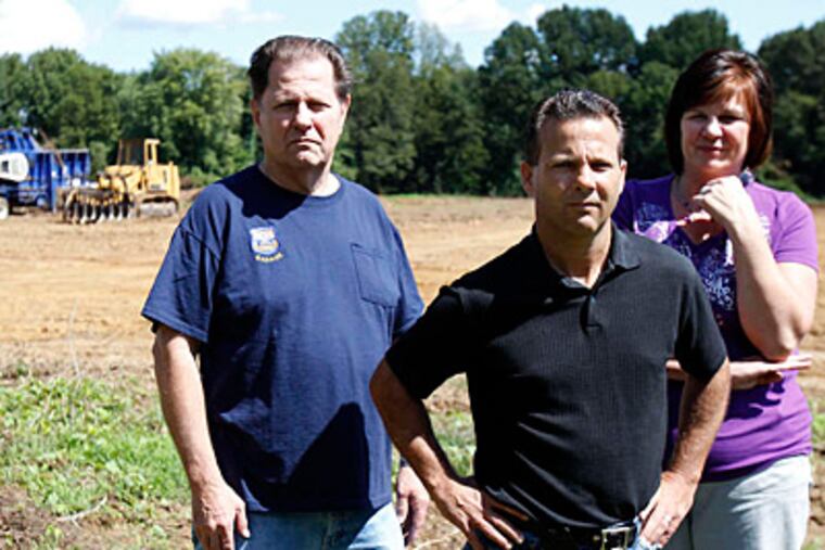 Ray Kampf (from left), Joe Brennan and Lisa George, each of whom has lived in Parkwood for four decades, stand Sunday near the formerly wooded area that was bulldozed to make room for a tour-bus parking lot. (David Maialetti/Staff Photographer)