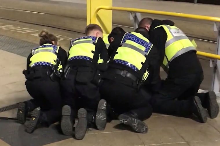 UGC issued by PA shows Police restraining a man after he stabbed three people at Victoria Station in Manchester, England, late Monday Dec. 31, 2018. Two commuters - a man and woman in their 50s - were taken to hospital with knife injuries and a British Transport Police (BTP) officer was stabbed in the shoulder. Police said a man was arrested on suspicion of attempted murder and remains in custody. (Sam Clack/PA via AP)