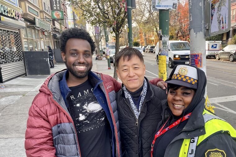 Scott Lee (center), who owns Lee's Deli at 47th and Baltimore in West Philly, with customers and friends Samuel Amare (left) and Renee Pettis (right). A fixture on the corner for nearly 30 years, the deli was forced to close after it was severely damaged by a speeding van on Nov. 20. Lee said he hopes to reopen next year.