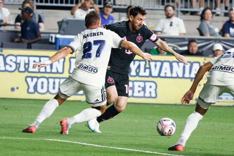Lionel Messi (center) on the ball in front of Kai Wagner during the first half.