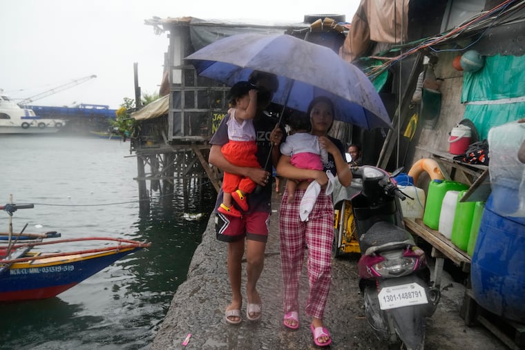 Residents carry their children as they evacuate to safer grounds to prepare for the coming of Typhoon Noru at the seaside slum district of Tondo in Manila, Philippines, Sunday, Sept. 25, 2022. The powerful typhoon shifted and abruptly gained strength in an "explosive intensification" Sunday as it blew closer to the northeastern Philippines.