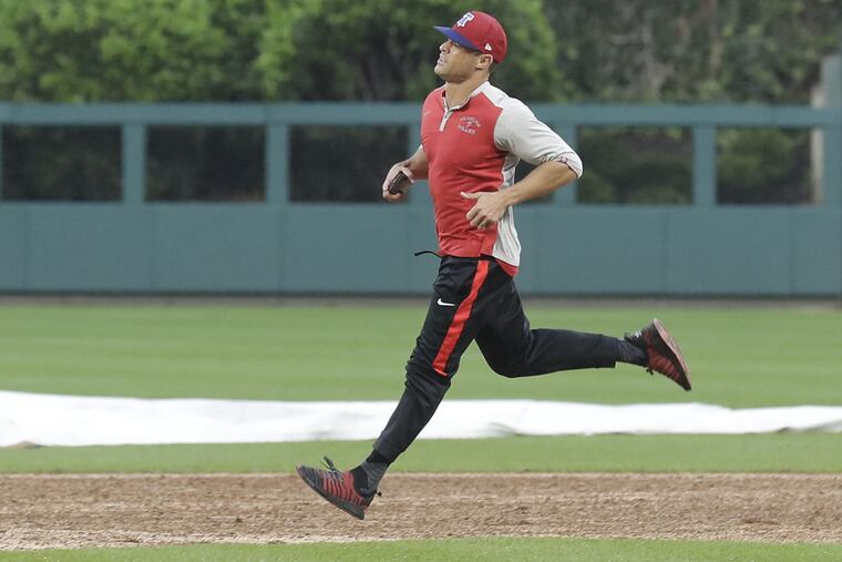 Phillies manager Gabe Kapler runs the infield after grounds crew members worked to dry the field Monday night.