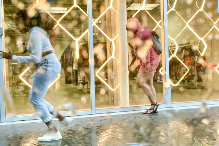 Pedestrians run for cover from a sudden downpour by Third and Race Streets in Philadelphia on Thursday. The region is under a severe thunderstorm watch this evening.
