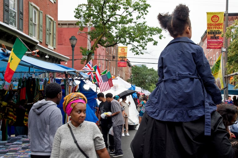 Freedom Reign, 5, rides along South Street on the shoulders of her father, Manani Akbar of Northeast Philadelphia, during the annual Odunde Street Festival along South Street Sunday.