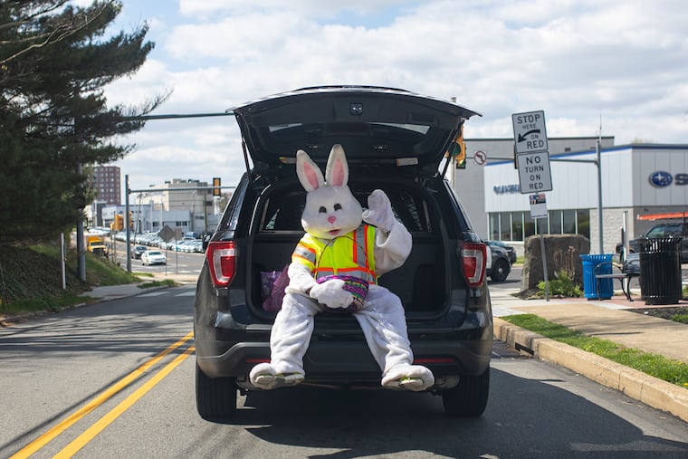 Anthony Matteo, 32, of Southampton, Pa., K9 Police Officer, playing as the easter bunny, sits in the open trunk of a Police vehicle to hop out and deliver a sweet treat to the kids in Jenkintown, Pa., on Saturday, April 11, 2020. Patrol Officer Cory Murtagh, 33, of Boyertown, Pa., came up with the idea to drive around with the Easter Bunny to do a community outreach and make light of things during the coronavirus outbreak.