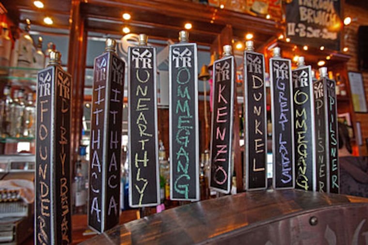 Beer taps with handwritten names at the South Philadelphia Taproom at Mifflin and South Hicks. The bar has 14 fresh taps and a 70-bottle list. (DAVID M WARREN / Staff Photographer)