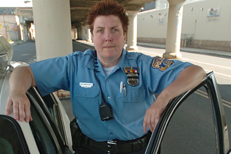 Officer Sharon Brambrinck stands at her patrol car while working in the 17th District. (Clem Murray/Inquirer)