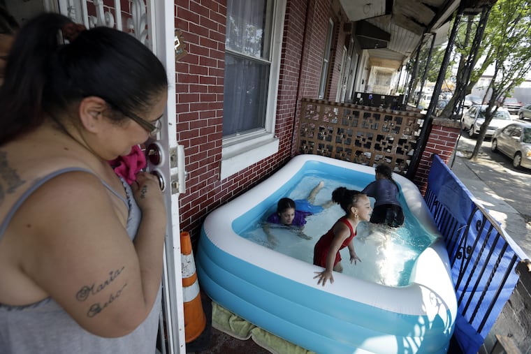 Luz Pratts, left, watches her daughters Karina, 11, Amarilys, 9, background, play with Laylana, 3, in an inflatable pool on the front porch as they keep cool in the West Kensington neighborhood of Philadelphia, Monday July 2, 2018. The National Weather Service has issued an excessive heat warning through Tuesday in the Philadelphia area with oppressive temperatures expect to last through the Fourth of July holiday. (AP Photo/Jacqueline Larma)
