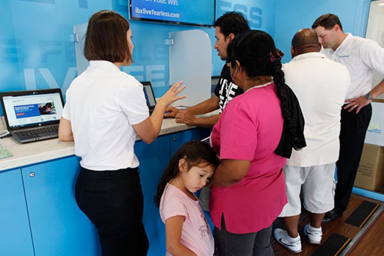Nidia Garrido (center) with granddaughter Daniella Hozada, 5, gets some information on the new health care law during a visit to the Blue Cross Independence Express bus parked outside the Rising Sun Health Center. ( MICHAEL S. WIRTZ / Staff Photographer )
