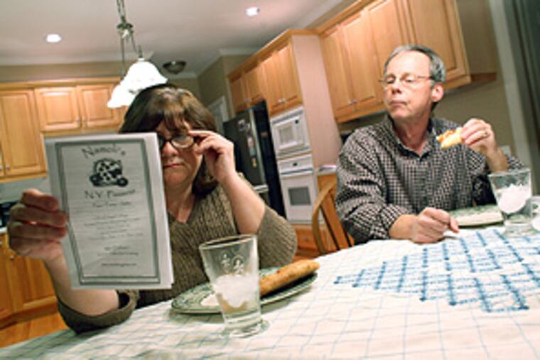 Amy Dunn and her husband, Mark Dunn, look over a pizzeria menu while eating a take-out pizza dinner to celebrate the end of their "dollar diet." The family went the entire month of February with no discretionary spending. They used a coupon to purchase the pizza.