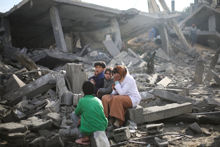 Palestinians sit by the destruction from the Israeli bombardment of the Gaza Strip in Rafah on Feb. 12. Progress toward peace and a two-state solution is unlikely before a change in the current Israeli and Palestinian leadership, writes Trudy Rubin.