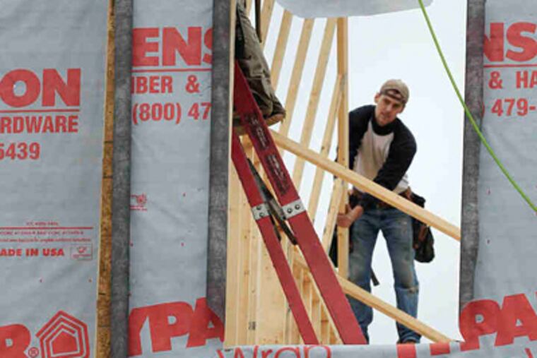 In Derry, N.H., builders place a roof panel on the second story of a home under construction,a sight that was less common during October, according to the Commerce Department. (Charles Krupa / AP)
