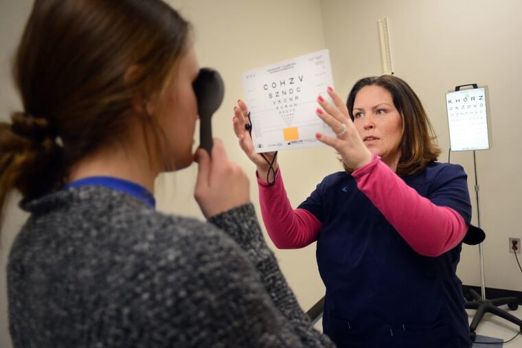 Bensalem High School Nursing Coordinator Jamie Thim gives an eye test to a 10th grade student.