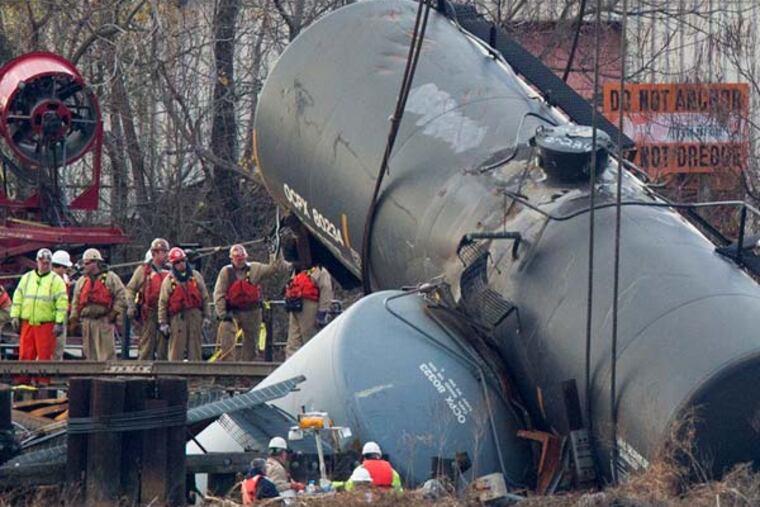 Work crews prepare to hoist the derailed tanker cars from the Mantua Creek in Paulsboro NJ. on the afternoon of Tuesday December 12th. A large crane was brought in to lift the emptied cars.( Ed Hille / Staff Photographer )